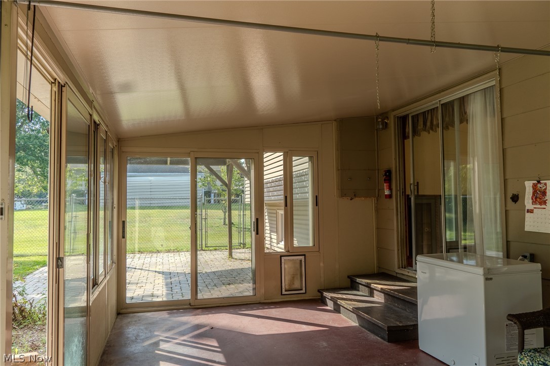 2848 Pressler Road Uniontown, OH 44685 - Photo 8 of 37 Enclosed sunroom featuring multiple sliding glass doors, a solid ceiling, and steps leading to an interior doorway