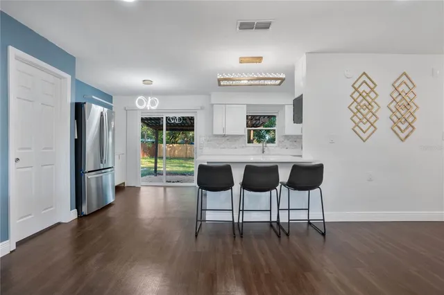 a kitchen with stainless steel appliances wooden floor and chairs