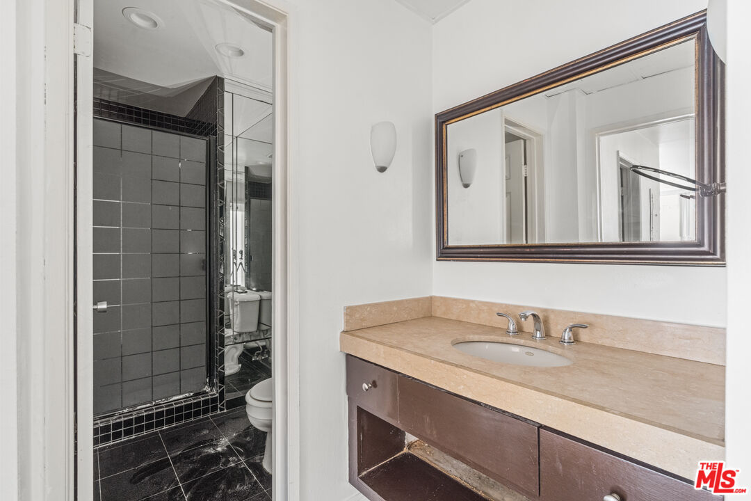 10747 Wilshire Boulevard, Unit 805 Los Angeles, CA 90024 - Photo 11 of 14 a bathroom with a granite countertop sink a mirror and shower