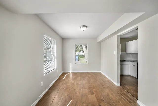 a view of empty room with wooden floor and fan