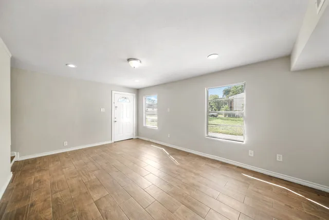 an empty room with wooden floor and windows