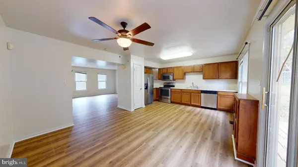 a large kitchen with stainless steel appliances a large window a wooden floor and a glass door