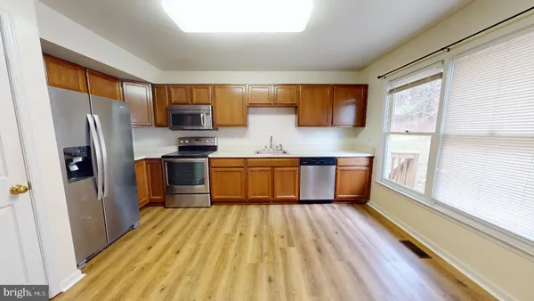 a kitchen with stainless steel appliances a refrigerator sink and wooden floor