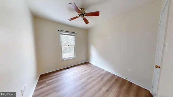 an empty room with ceiling fan and window