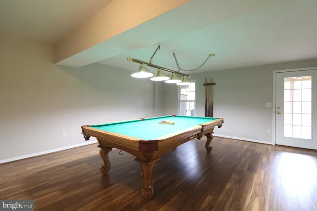 an room with pool table window and wooden floor