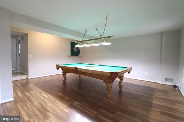 a room with wooden floor pool table and window