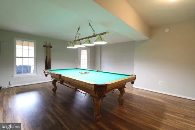 an room with pool table window and wooden floor