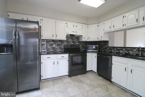 a kitchen with a refrigerator sink and cabinets