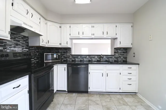 a kitchen with stainless steel appliances granite countertop a stove a sink and a white cabinets