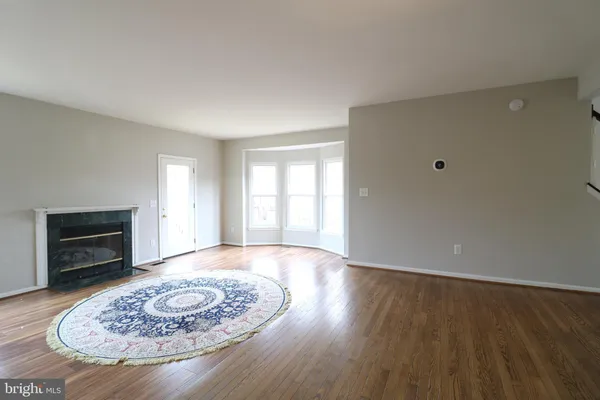 an empty room with wooden floor fireplace and window
