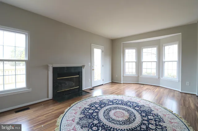 an empty room with windows fireplace and wooden floor