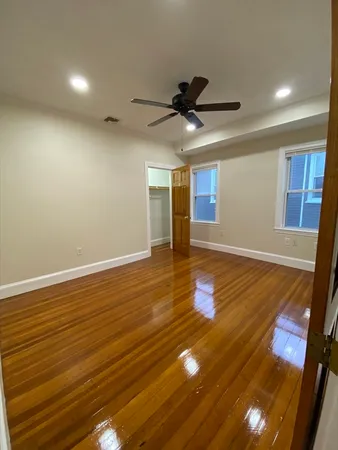 a view of empty room with wooden floor and fan