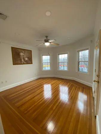 a view of an empty room with window and wooden floor