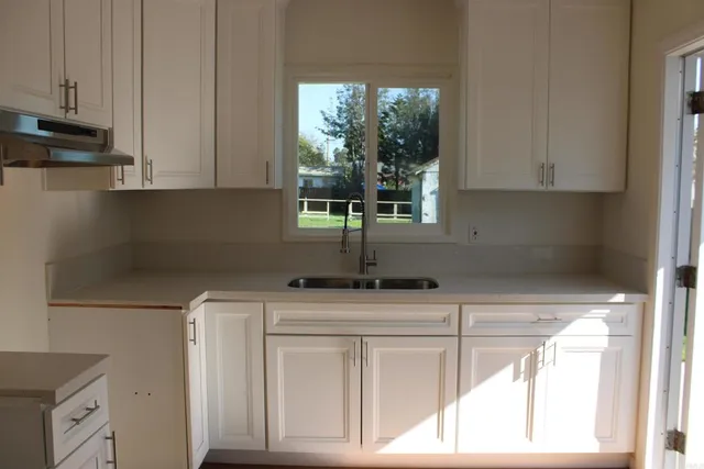 a kitchen with stainless steel appliances white cabinets and a window