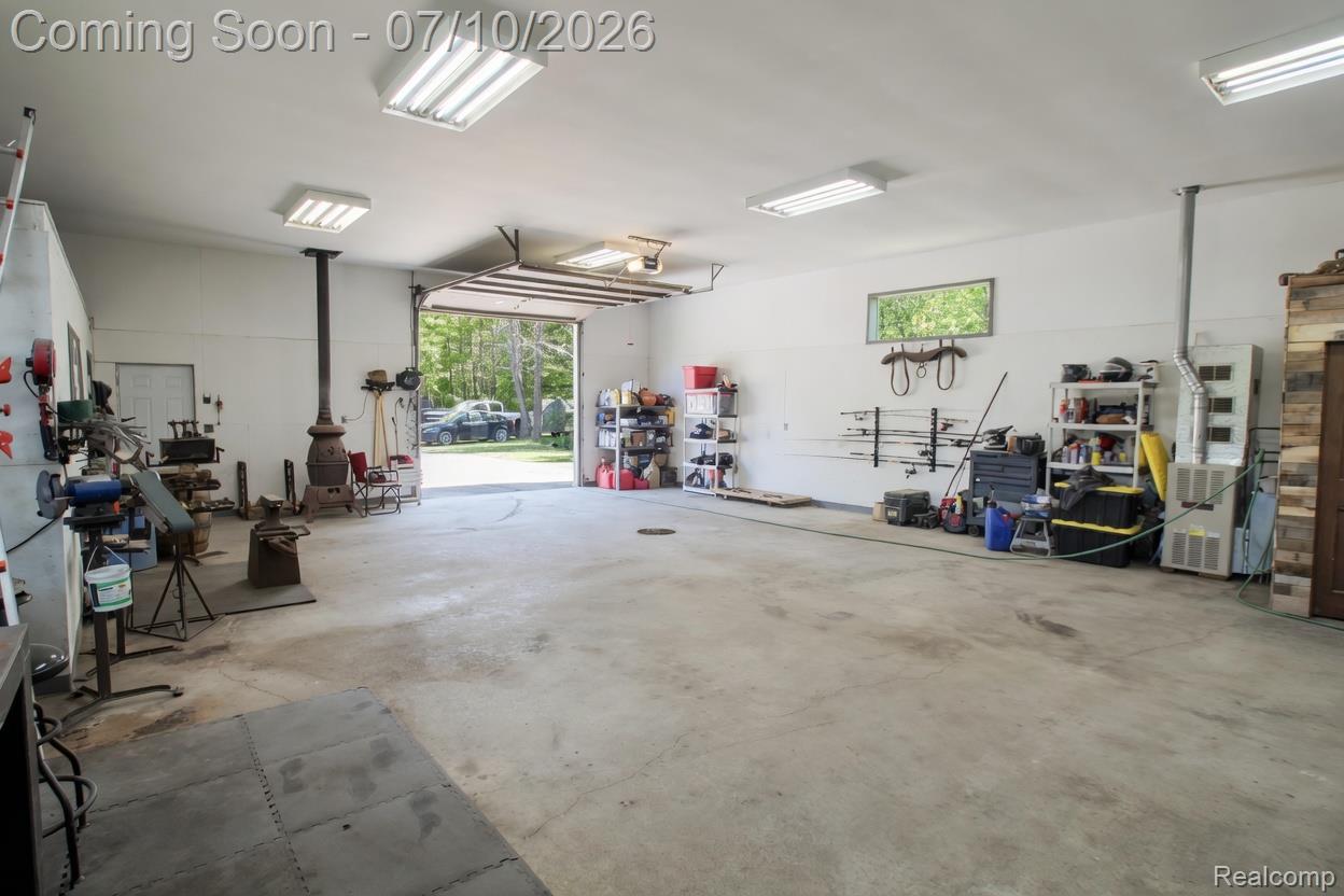 5278 Skelton Road Columbiaville, MI 48421 - Photo 19 of 64 Spacious garage with concrete flooring, multiple fluorescent light fixtures, and an overhead door
