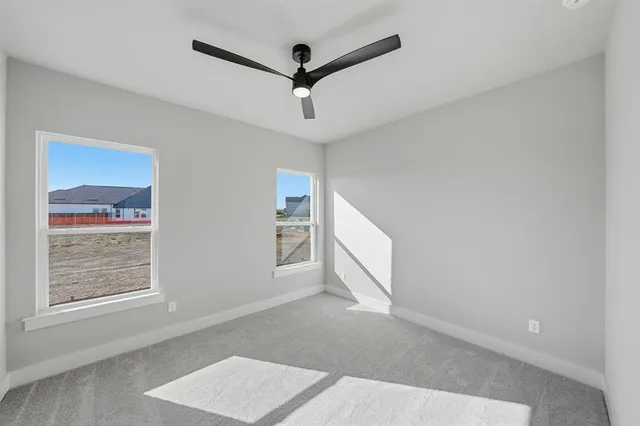 an empty room with windows and ceiling fan