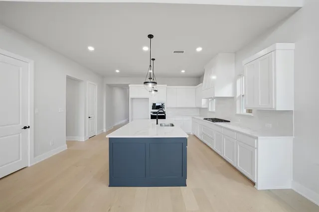 a large kitchen with kitchen island a stove a sink a center island and a refrigerator