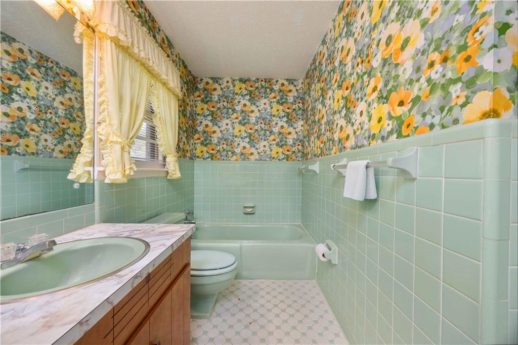 5201 Summerville Road Phenix City, AL 36867 - Photo 24 of 35 Bathroom with wallpapered walls, wainscoting, tile walls, a tub to relax in, and toilet