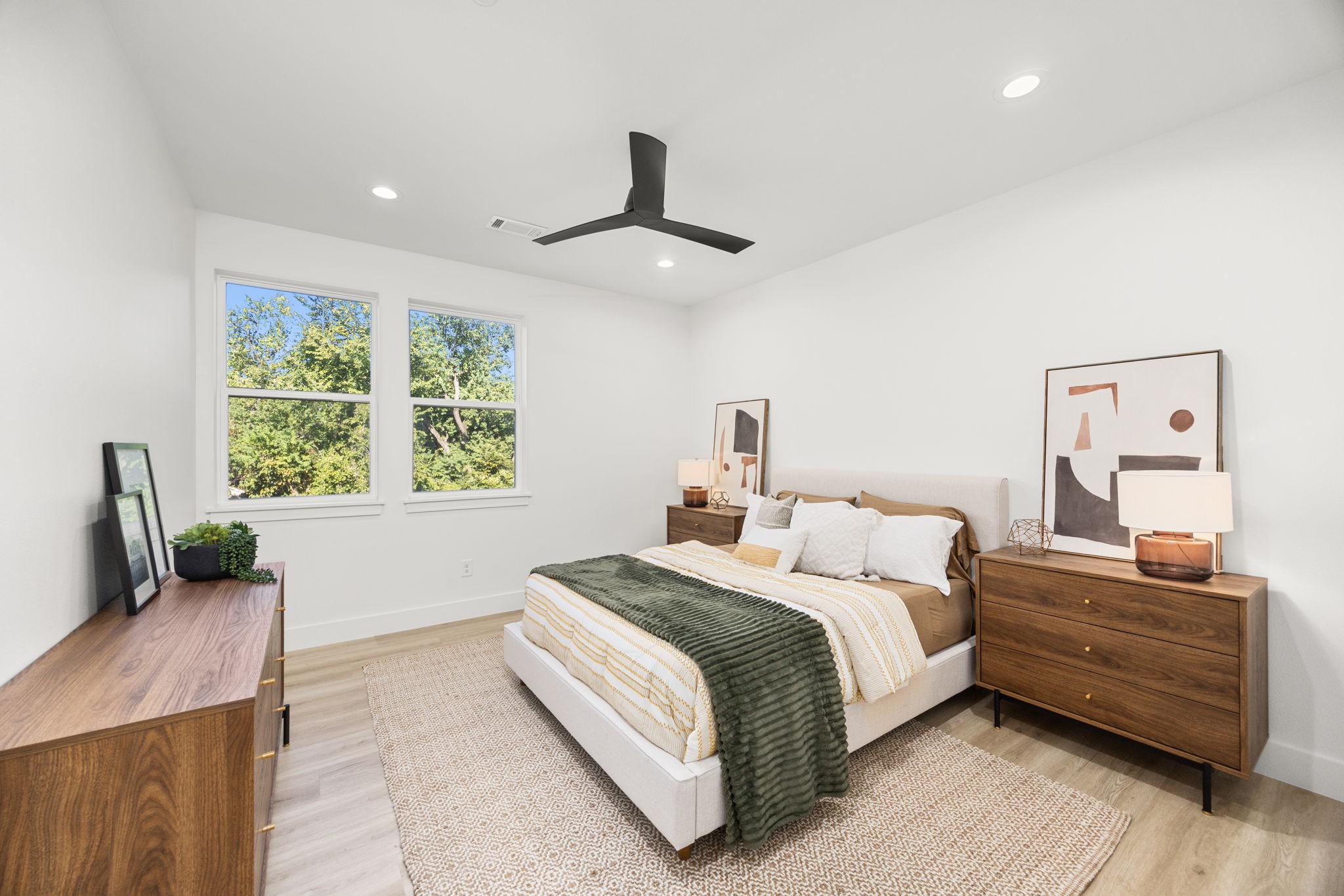 4611 Dewberry Street, Unit C Houston, TX 77021 - Photo 24 of 34 Bright and modern bedroom featuring a cozy bed, stylish wooden furniture, and large windows with a view of lush greenery. The space is enhanced by a sleek ceiling fan and minimalist decor.