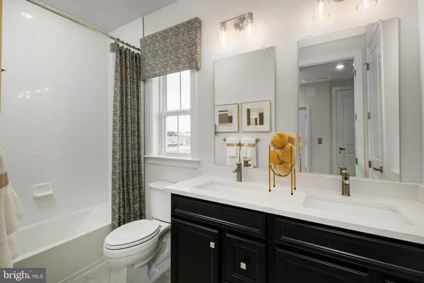 a bathroom with a double vanity sink toilet mirror and bathtub