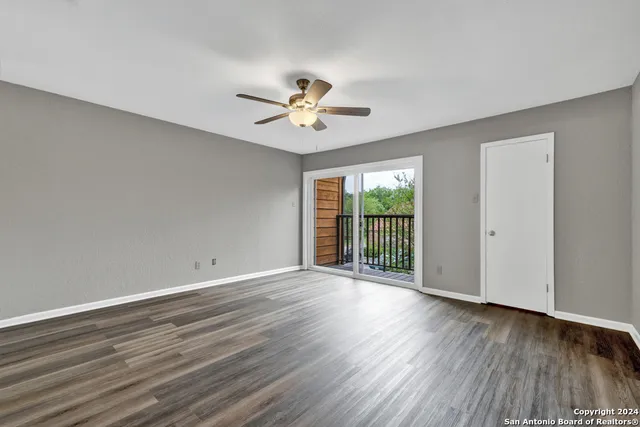 a view of an empty room with a window and wooden floor