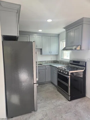 a kitchen with stainless steel appliances granite countertop a refrigerator a stove and a sink