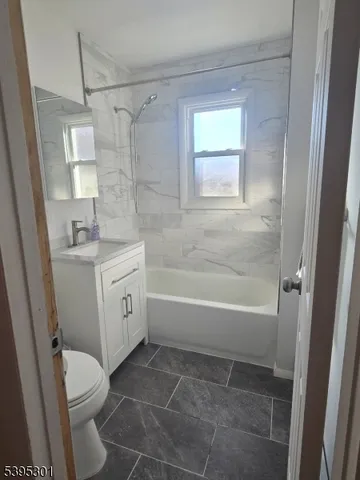 a bathroom with a granite countertop sink a toilet and shower