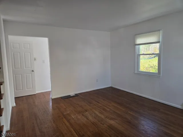an empty room with wooden floor and a window