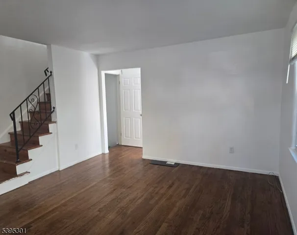 a view of an empty room with wooden floor and stairs