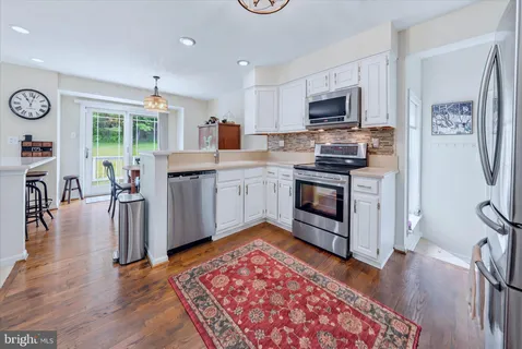 a large kitchen with stainless steel appliances granite countertop a stove and a wooden floors
