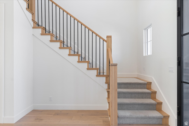 1192 East Corral Way Washington, UT 84780 - Photo 14 of 81 Hardwood staircase with light wood-finish treads and risers, featuring a carpet runner and wrought iron balusters
