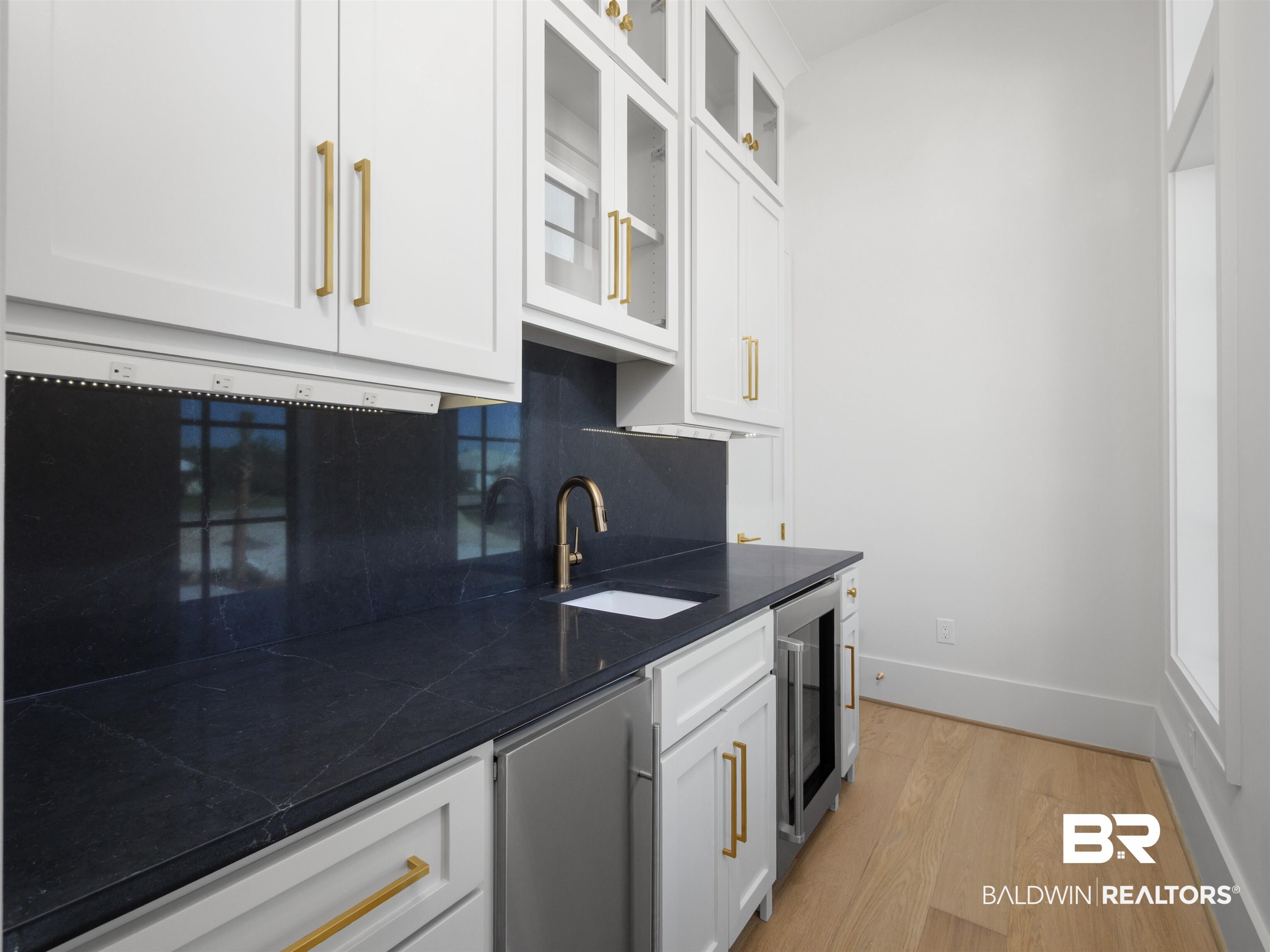31292 River Road Orange Beach, AL 36561 - Photo 5 of 48 Kitchen featuring wine cooler, dark countertops, backsplash, light wood-style floors, and a sink