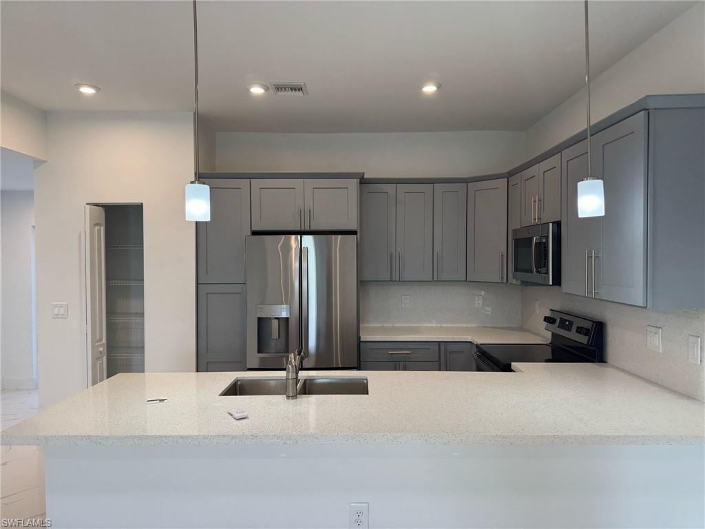 402 Grant Boulevard Lehigh Acres, FL 33974 - Photo 3 of 9 a kitchen with kitchen island a sink stainless steel appliances and cabinets
