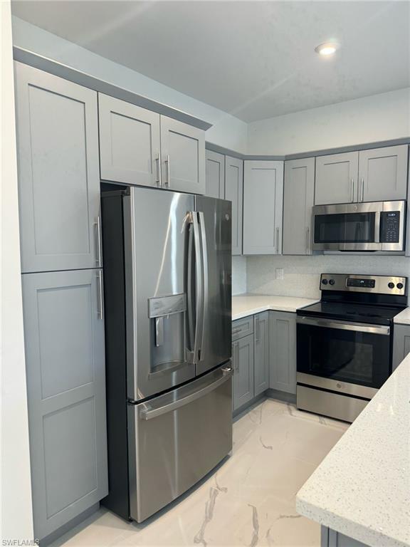402 Grant Boulevard Lehigh Acres, FL 33974 - Photo 4 of 9 a kitchen with stainless steel appliances a refrigerator and a stove top oven