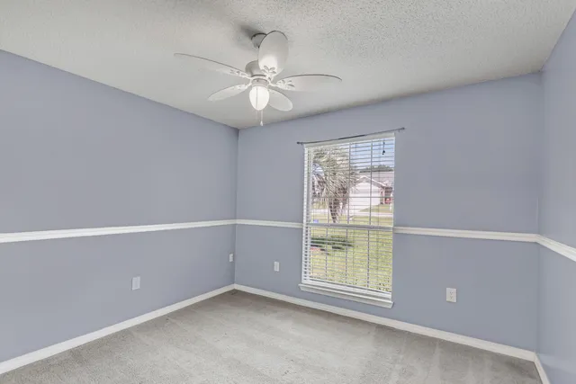 an empty room with windows and fan