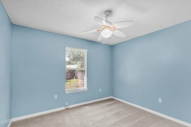 an empty room with windows and fan