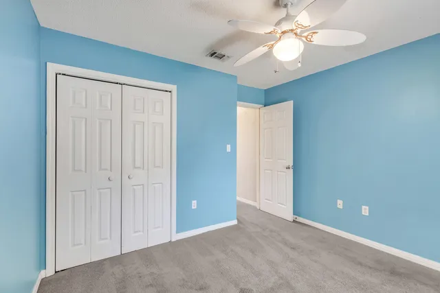 an empty room with closet and a ceiling fan