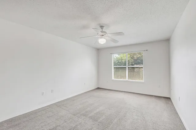 an empty room with a window and a fan