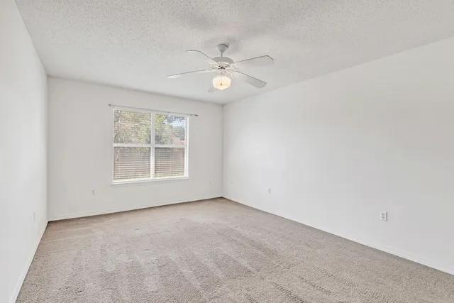 an empty room with a window and a ceiling fan