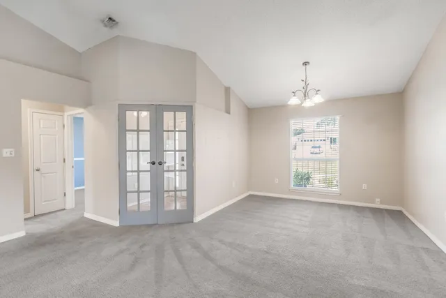 an empty room with windows and chandelier fan