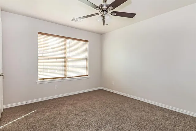 an empty room with a window and a fan