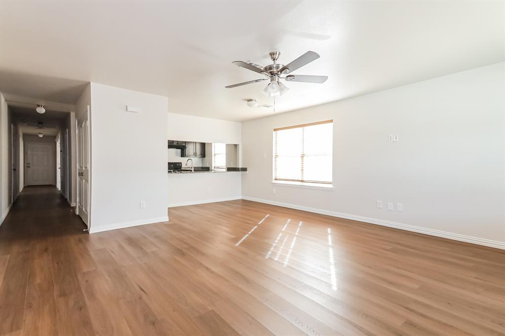 4712 Stokes Street Dallas, TX 75216 - Photo 3 of 16 an empty room with wooden floor a ceiling fan and windows