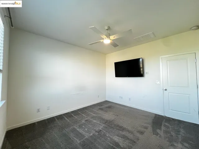 an empty room with a flat screen tv and a kitchen view