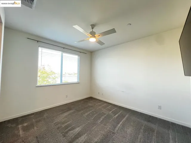 an empty room with a window and a ceiling fan