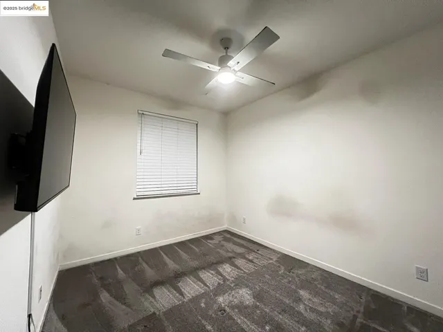 an empty room with a ceiling fan and window