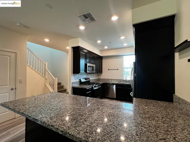 a kitchen with stainless steel appliances granite countertop a sink stove and refrigerator