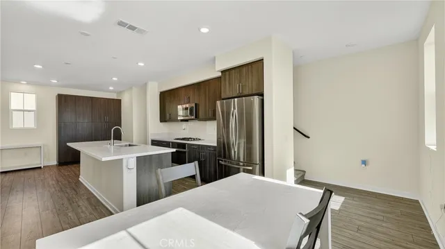 a kitchen with a refrigerator a stove top oven a sink dishwasher and wooden floor