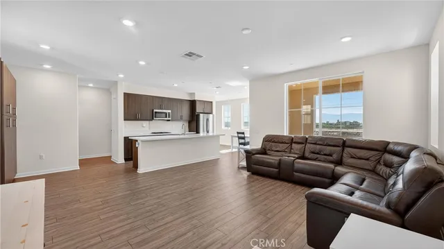 a living room with furniture and kitchen view with wooden floor