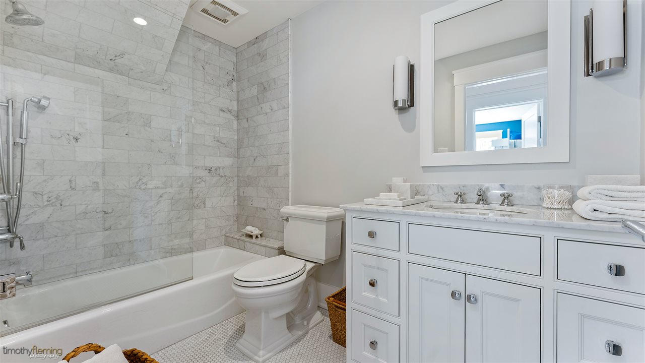 74 38th Street Avalon, NJ 08202 - Photo 14 of 39 a bathroom with a granite countertop toilet a sink a mirror a bathtub and shower