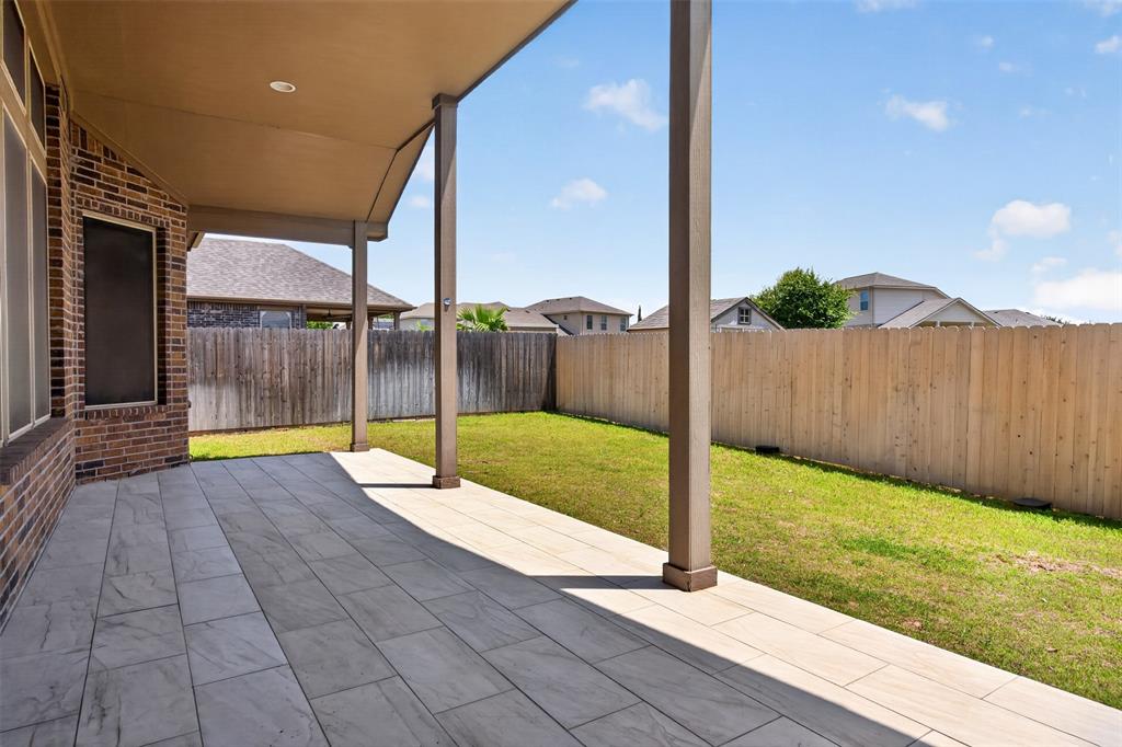 8728 Maple Ridge Trail Fort Worth, TX 76244 - Photo 3 of 40 Covered patio featuring rectangular tile flooring, brick exterior, and a fenced backyard with lawn